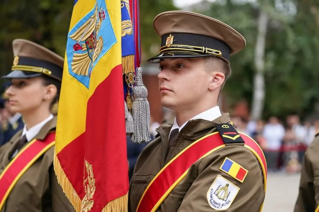 Elev militar în uniformă de ceremonie, lângă drapelul de luptă